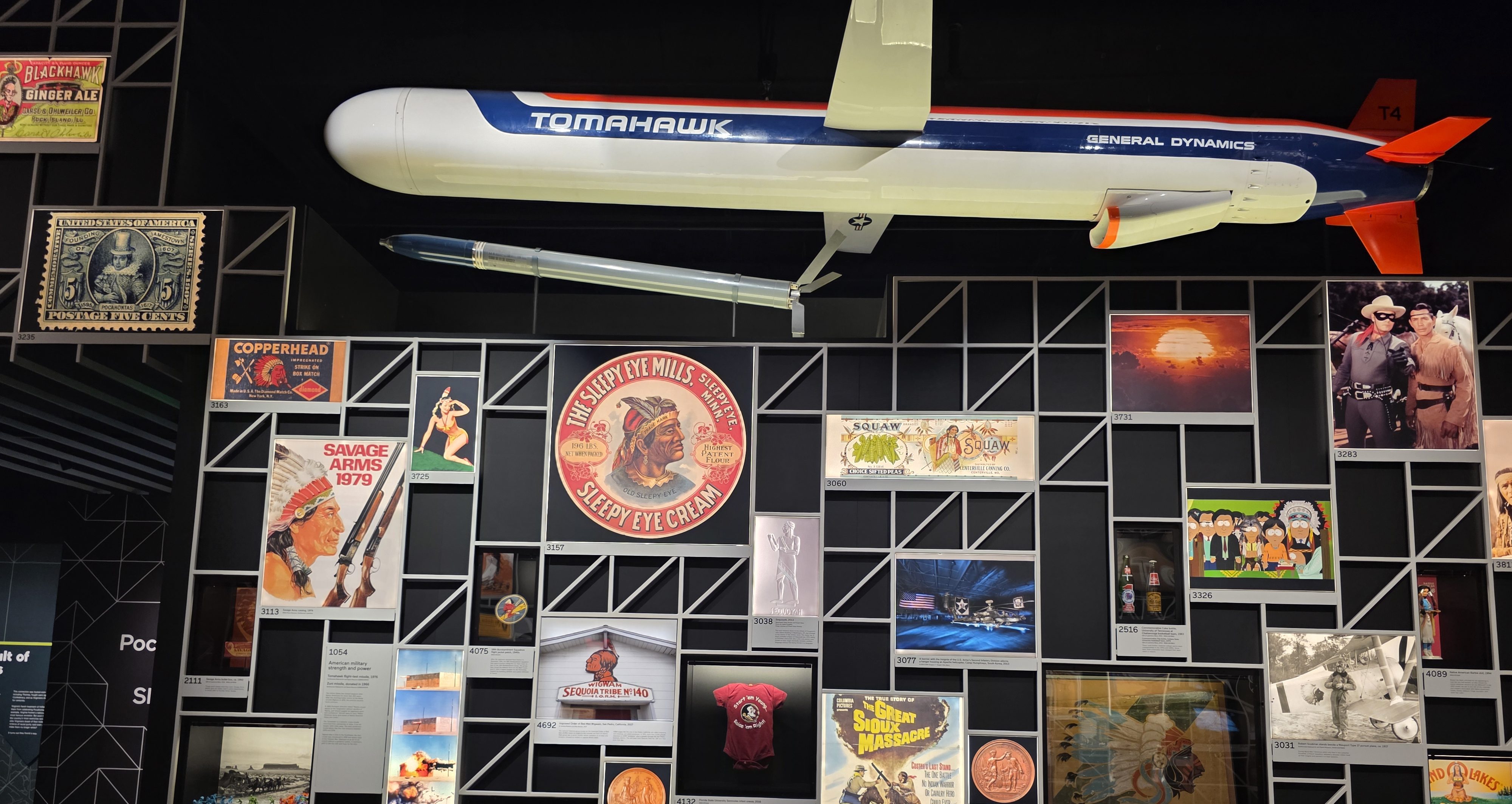 20260608_164103 GenAI Alt text: A large model of a Tomahawk missile hanging above a display wall with vintage posters and memorabilia